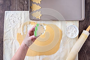 WomanÃ¢â¬â¢s hands cutting out Christmas tree sugar cookies, pastry cloth, cookie sheet